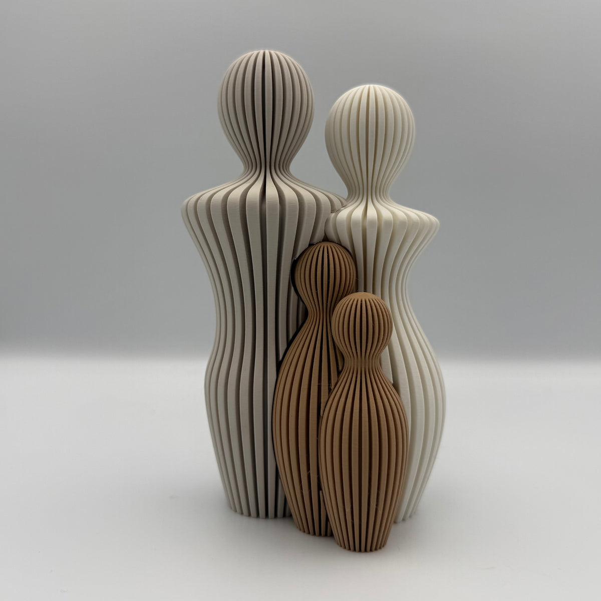 Familien, 3D-printet figur med to lyse voksne og to brune børn i ribbet design.
