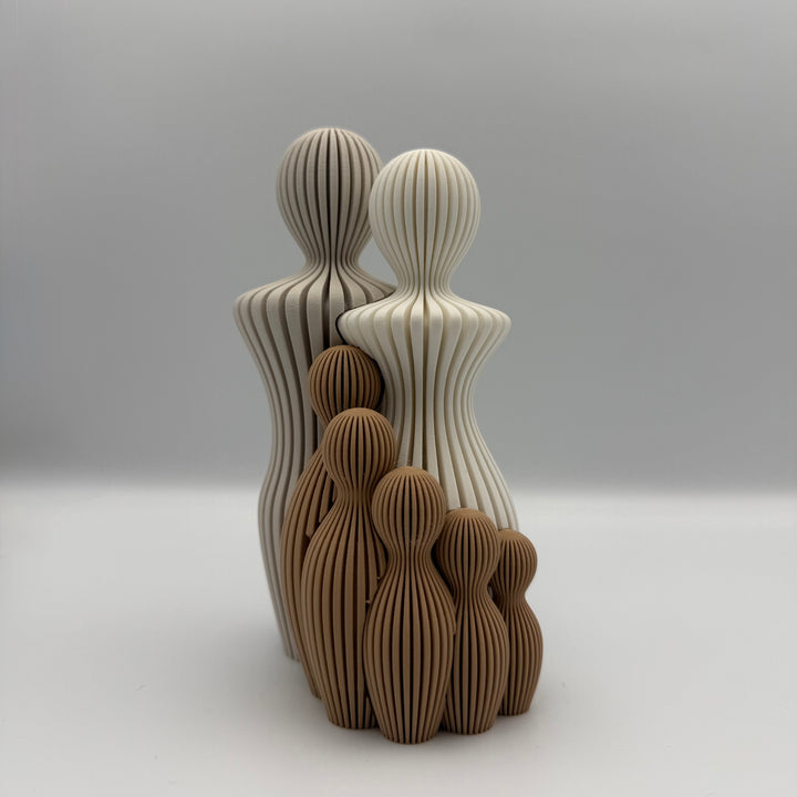 Familien, 3D-printet figur med to lyse voksne og fem brune børn i ribbet design.
