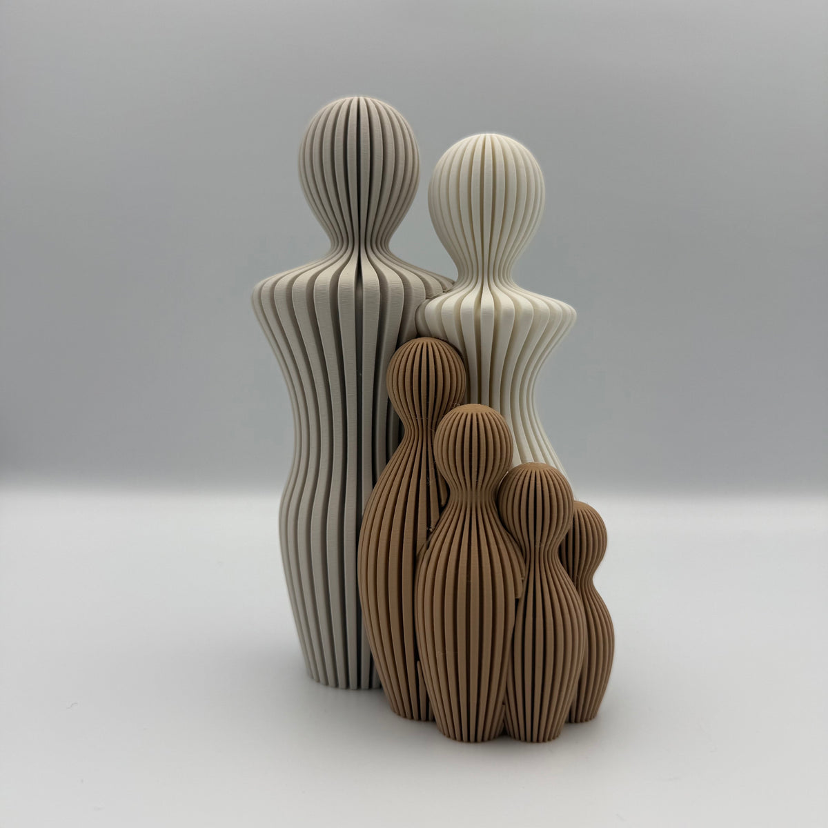 Familien, 3D-printet figur med to lyse voksne og fire brune børn i ribbet design.
