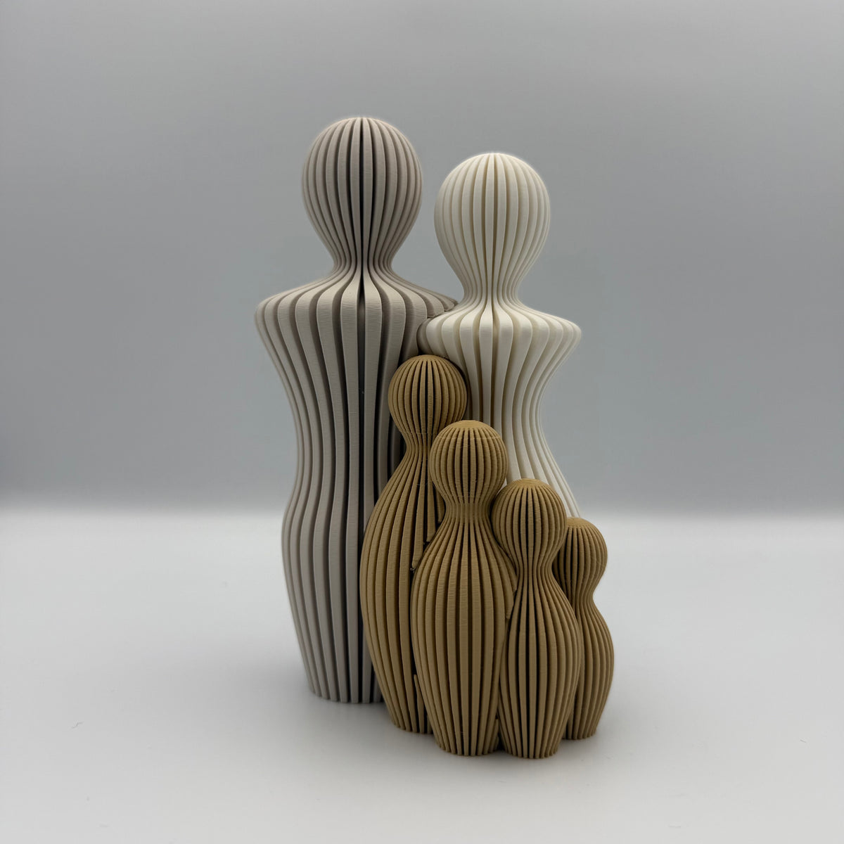Familien, 3D-printet figur med to lyse voksne og fire brune børn i ribbet design.
