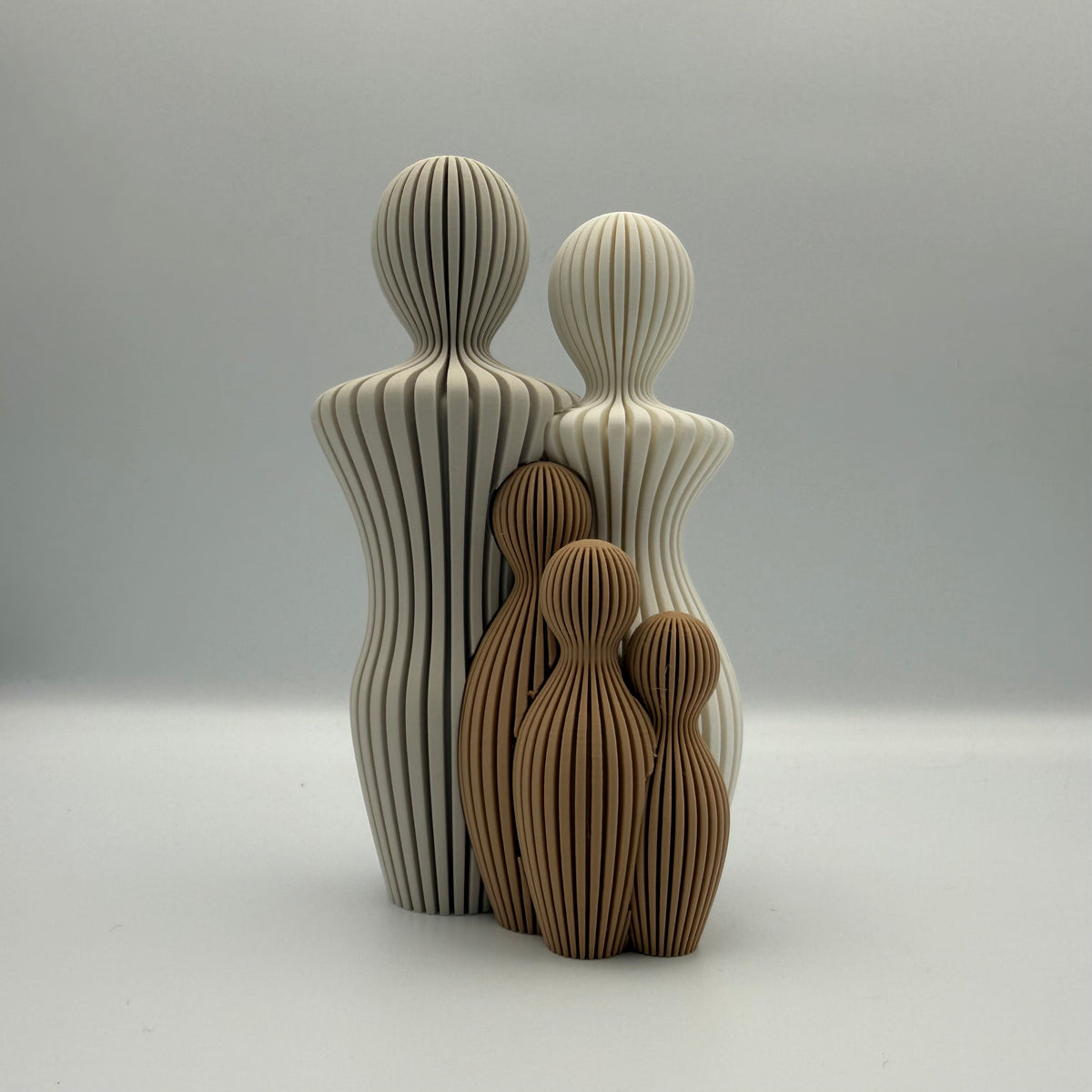 Familien, 3D-printet figur med to lyse voksne og tre brune børn i ribbet design.

